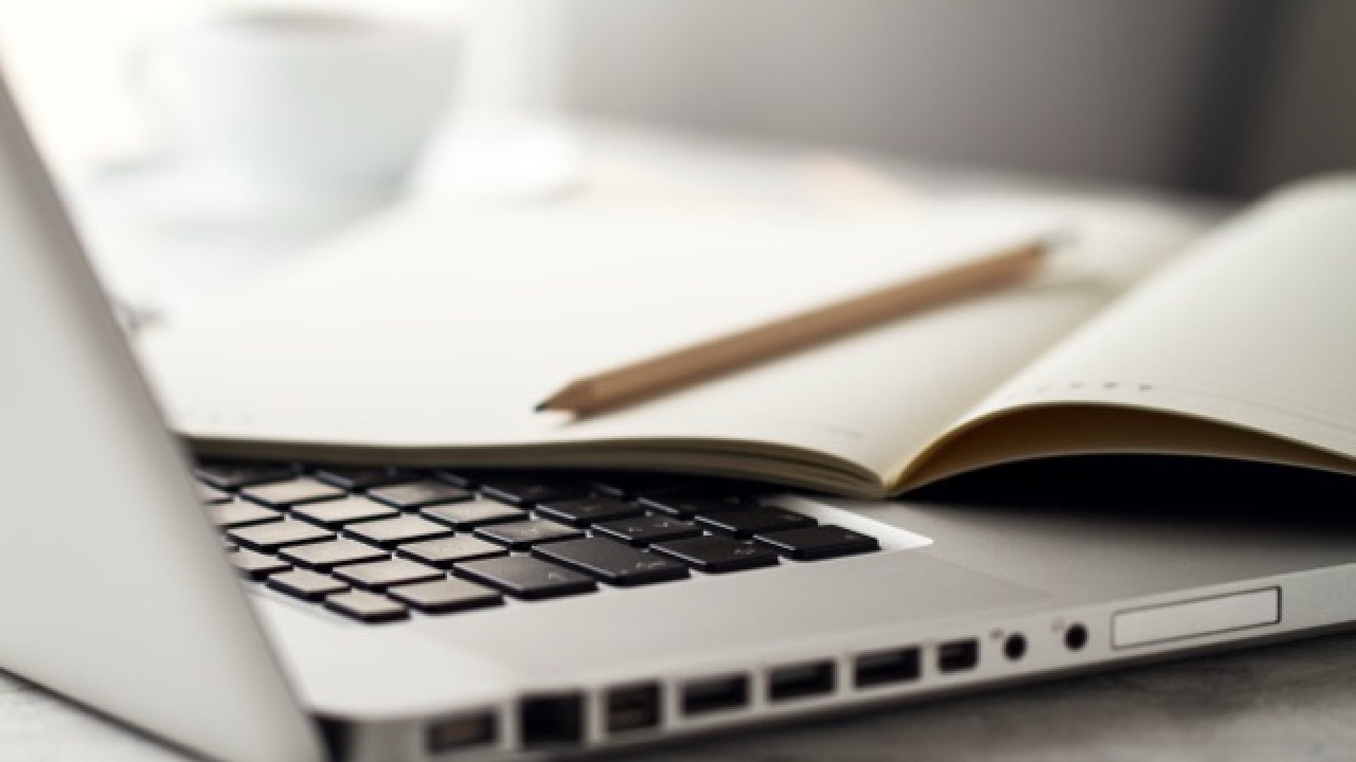 Closeup of Workspace with Modern Creative Laptop, Cup of Coffee and Pencils. Horizontal with Copy Space.